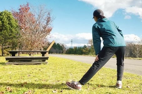 秋の青空の下でストレッチをする人。体と心を整える秋の運動の象徴。