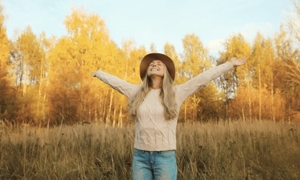 秋の自然の中で両手を広げて深呼吸する女性の写真