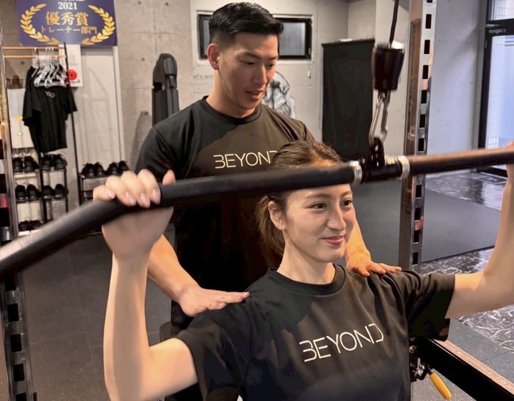BEYOND武蔵小杉のトレーナーが顧客にフォーム指導を行う様子。清潔感のある店内。