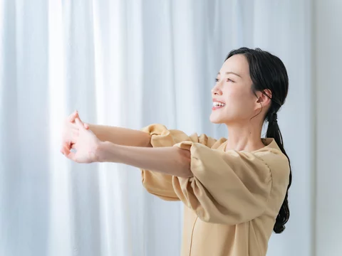 室内で朝にストレッチをして体を温める女性の写真