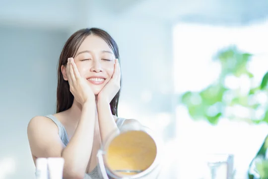 スキンケア後に肌の潤いを感じて微笑む女性