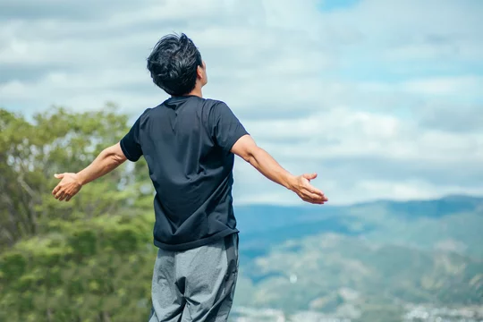 禁煙1日目から変わる体の変化。新鮮な空気を胸いっぱいに吸い込む男性の後ろ姿。