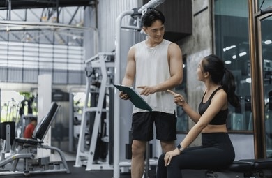 パーソナルトレーナーが禁煙サポートを行うジム風景。習慣化の重要性を伝える。