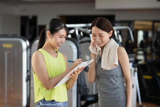 「女性がトレーナーと笑顔で相談している様子」