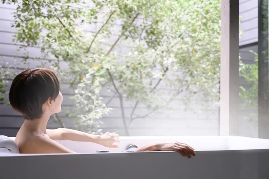「湯船につかって体を温めリラックスする女性」