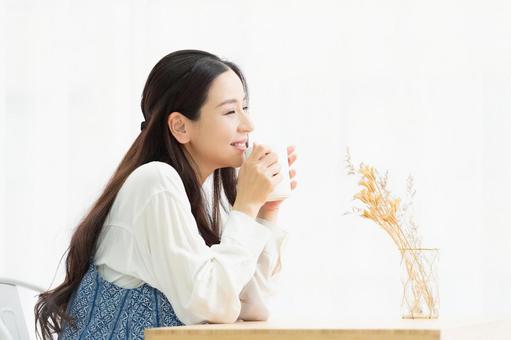 「温かい飲み物を飲みながら体を温める女性」