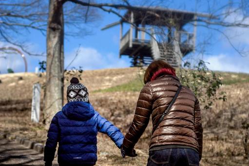「冬の公園を親子で手をつないで散歩している後ろ姿」