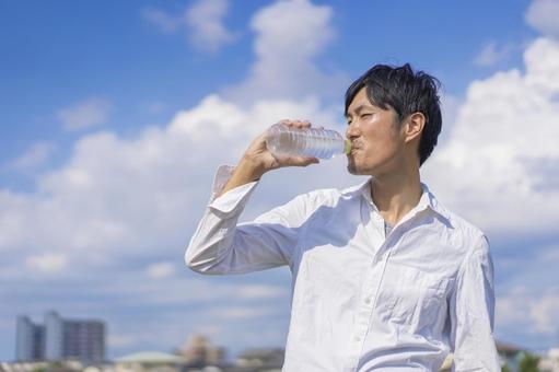 屋外でペットボトルの水を飲む男性