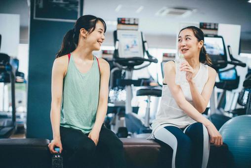 ジムでトレーニング前に会話をしている女性