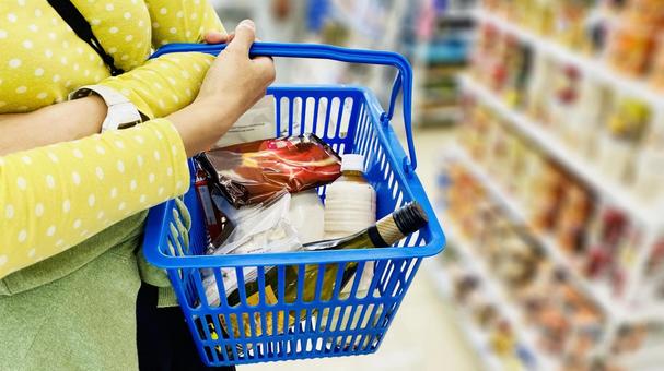 「スーパーで買い物カゴを持ち、お菓子や食品を選んでいる様子」